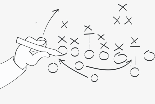 Hand drawing a strategic play diagram with X’s and O’s — symbolizing a marketing plan during a downturn